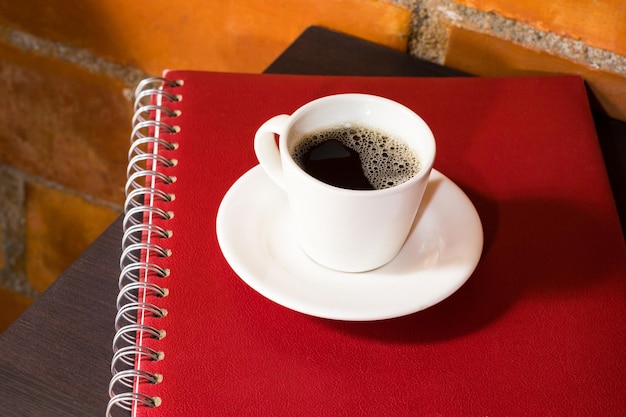 International coffee day traditional colombian drink coffee mug on notebooks on bedside table top view