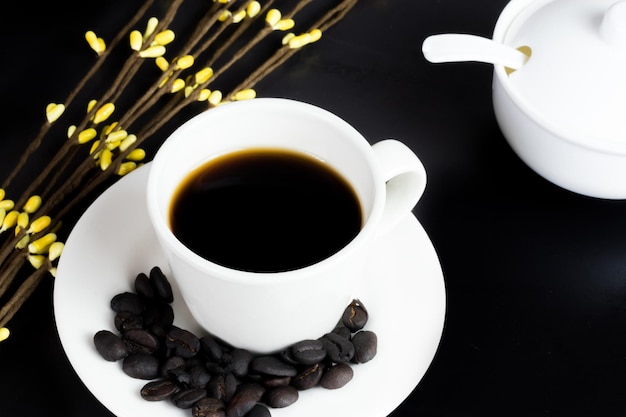 International coffee day traditional colombian drink top view of mug of coffee with roasted coffee beans and sugar bowl on black table decorated with flowers