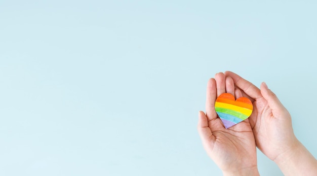 International Day Against Homophobia Transphobia and Biphobia Heart with rainbow LGBT flag in hands