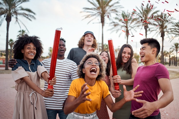 An international group of young people celebrate with confetti outside concept of celebration party