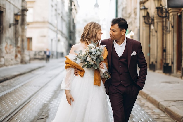 An international wedding couple a European bride and an Asian groom walk around the city together