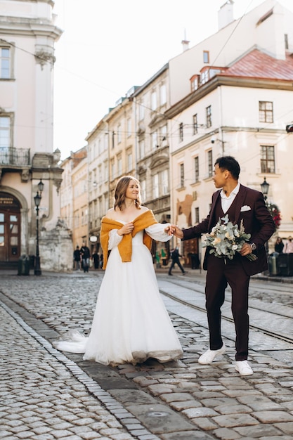 An international wedding couple a European bride and an Asian groom walk around the city together