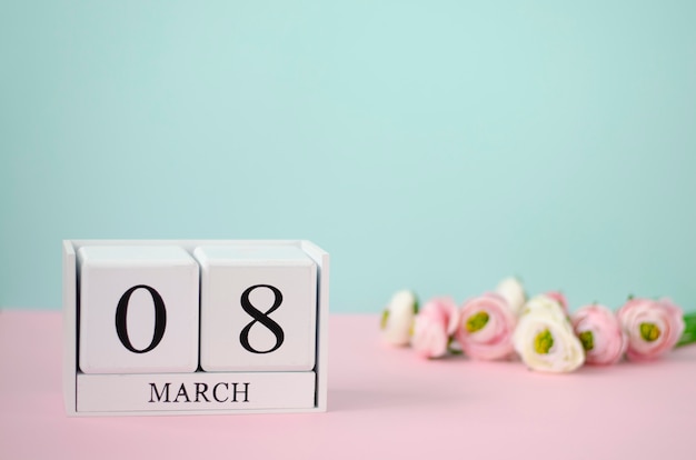 International Women's Day concept. White wooden cubes with 8th march and flowers on pastel background. 