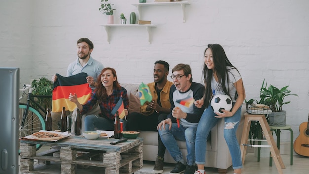 International young friends football match on TV together at home Most of them happy about German team winning but Brazilian man disappointed