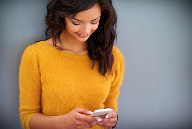 Photo internet happy and woman with phone in studio for social media notification and online post smartphone smile and female person with technology for contact text message or chat on gray background