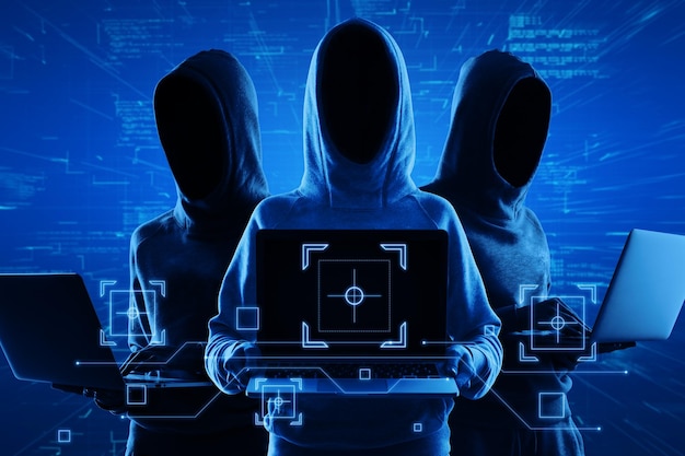 Internet security and personal data theft concept with blue shadows faceless hackers in hoody using laptop and abstract virtual technological symbols