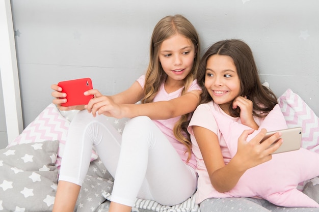 Internet surfing and absence parental advisory Smartphone internet access Girls sisters wear pajama busy with smartphones Children in pajama interact with smartphones Application for kids fun