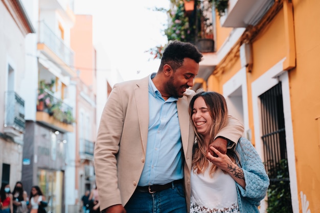 Interracial couple of an African American boy and a Caucasian girl walking down the street while looking happy