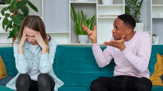 Interracial couple fighting at home boyfriend shouting at girlfriend she puts her hand on her head Stressed out couple having problems Divorce concept