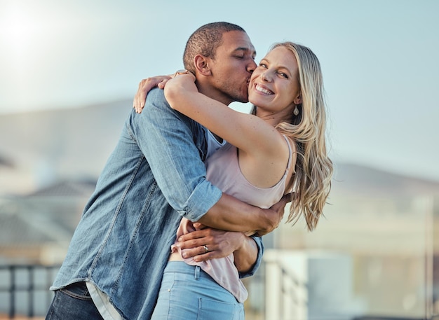 Interracial couple kiss and hug outdoor for romance relationship and happiness together Portrait woman and man hugging with affection support and trust in marriage love and commitment in city