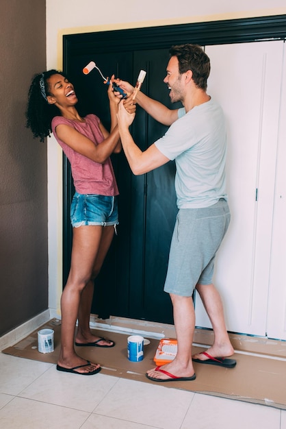 Interracial couple painting a wardrobe