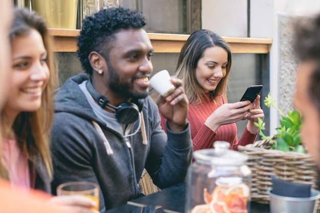 Interracial friends drinking coffee sitting at the table and having fun together