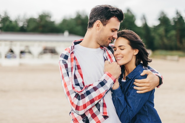 Intimate couple embracing on a quiet beach man holding womans arm tenderly both with joyful expressions of closeness and comfort