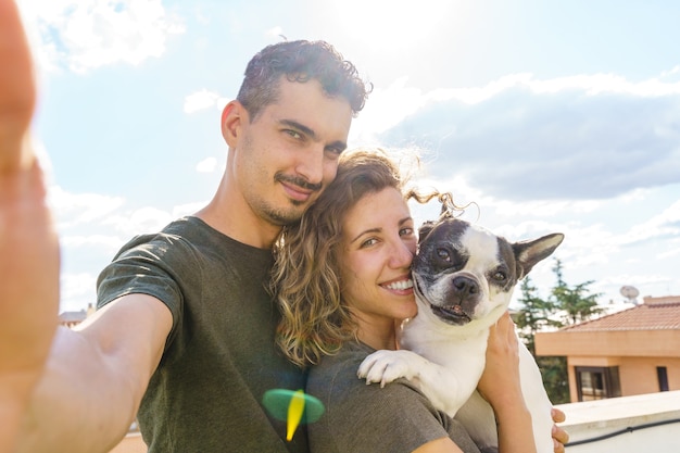 Intimate moment of couple with pet outdoors. Horizontal view of friends playing with bulldog.