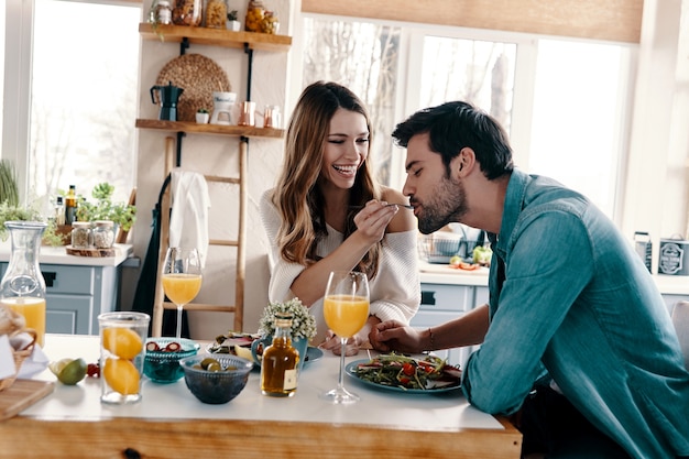 Intimate moments. Beautiful young couple enjoying healthy breakfast while sitting in the kitchen at home