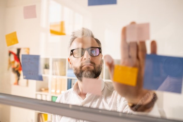 Introspective businessman joining stickers on glass