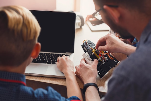 Inventions and creativity for kids. Unrecognizable boy programming robots on laptop with teacher. Stem education. Early development, diy, innovation, integrated education, modern technology concept