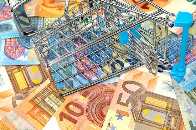 Inverted empty shopping cart on euro banknotes. concept of high cost food basket or purchasing power