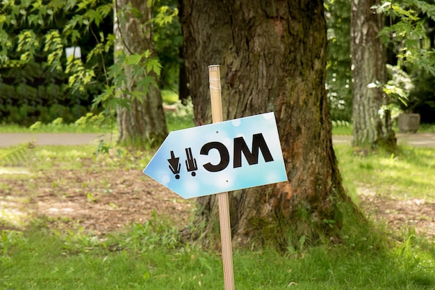 Inverted signpost with the inscription WC in the park