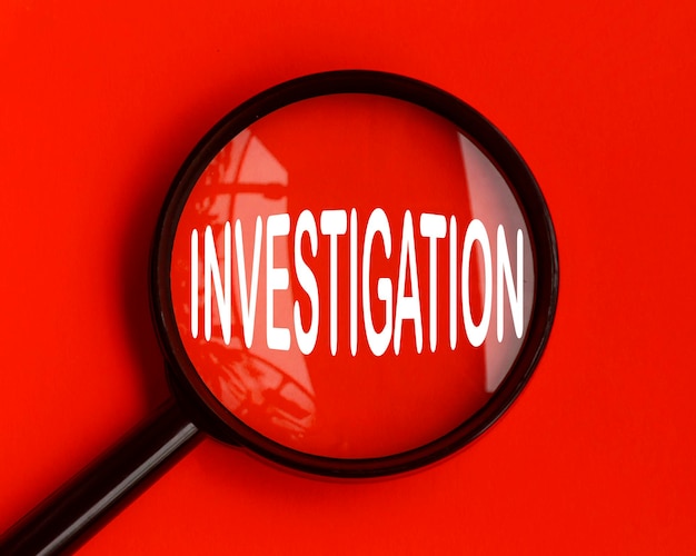 Investigation text on red cover with magnifying glass Scamming and fraud concept