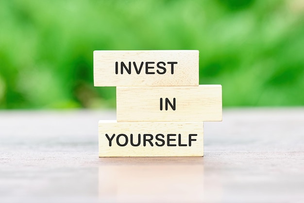 Investing in yourself Text on wooden blocks on a green background