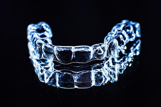 Invisible dental teeth brackets tooth aligners on black background Plastic braces dentistry retainers to straighten teeth