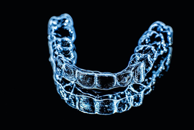 Invisible dental teeth brackets tooth aligners on black background Plastic braces dentistry retainers to straighten teeth