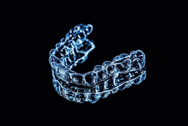 Invisible dental teeth brackets tooth aligners on black background Plastic braces dentistry retainers to straighten teeth