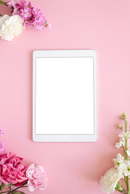 Ipad pro tablet with white screen on pink color background flowers office design woman background