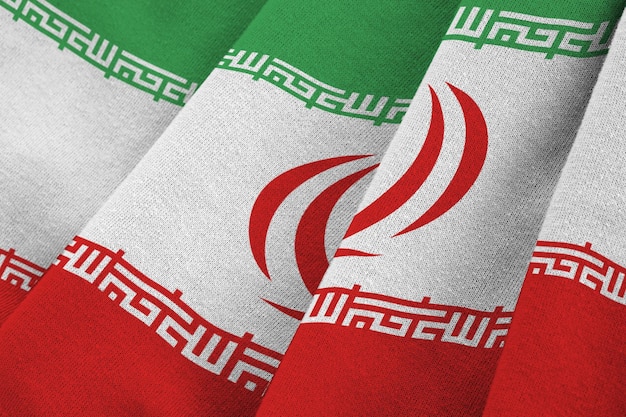 Iran flag with big folds waving close up under the studio light indoors The official symbols and colors in banner