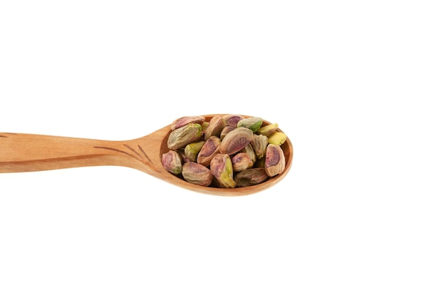 Iranian pistachios in wooden spoon closeup Side view Peeled Green pistachio on white background.