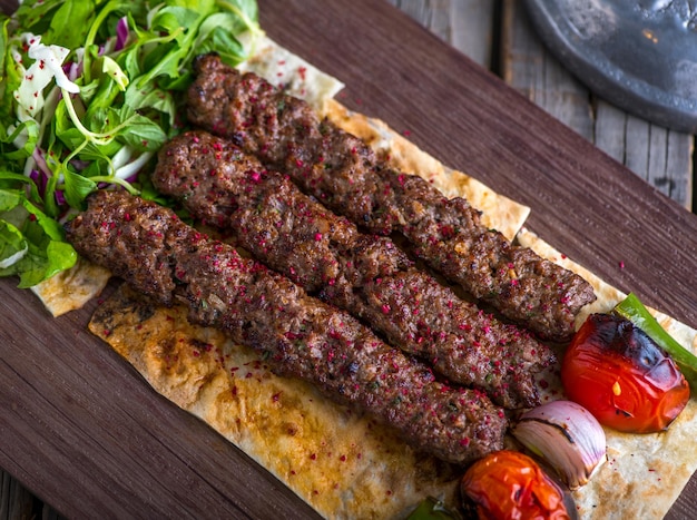 Iraqi beef seekh kabab platter served in dish side view on wooden table background