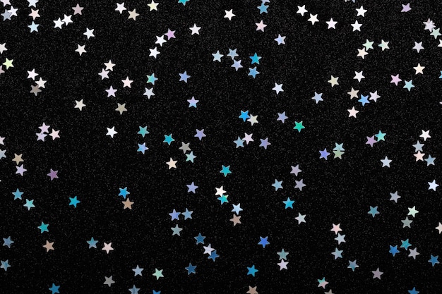 Iridescent Silver stars confetti on black Festive background Glowing sparkles.