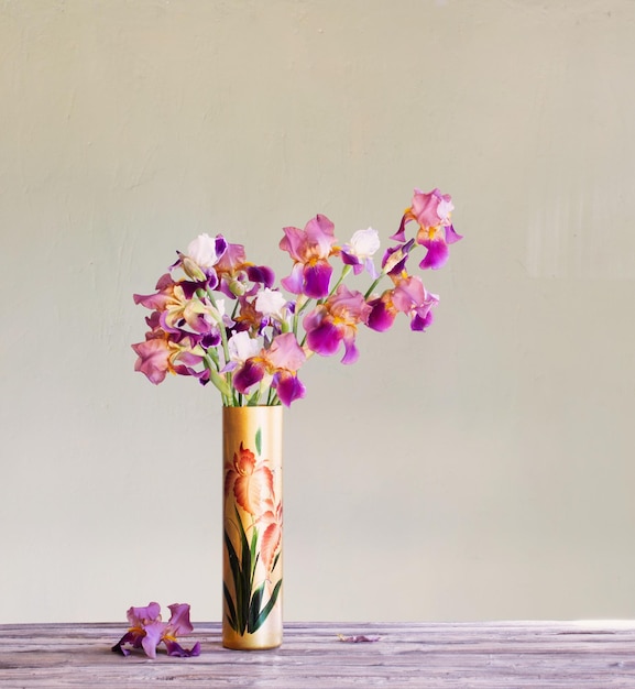 Irises in beautiful glass vase against green wall