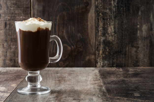 Irish coffee in glass on wooden table copy space