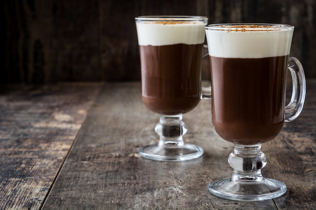 Irish coffee in glass on wooden wall 