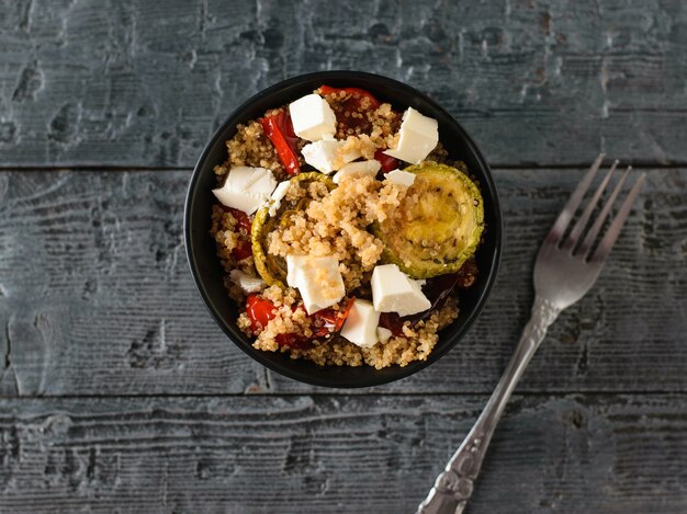 Iron fork with salad of boiled quinoa, baked vegetables and baked vegetables