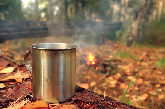 iron mug with hot tea on a camping trip active lifestyle autumn yellow park