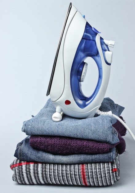 Iron on stack of clothes on gray table