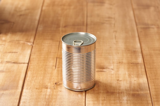 Iron tin can with tab opener on the wooden table.