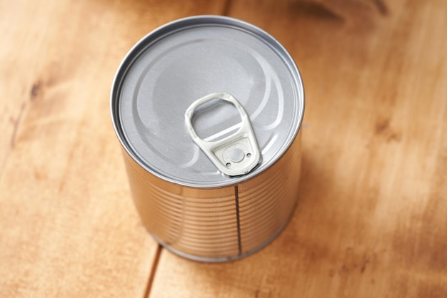 Iron tin can with tab opener on the wooden table.