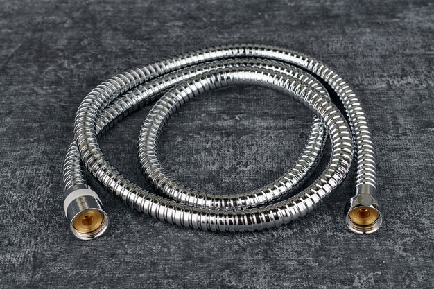 Iron water hose for shower on grey background, close up