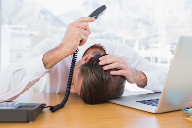 Irritated businessman holding the phone