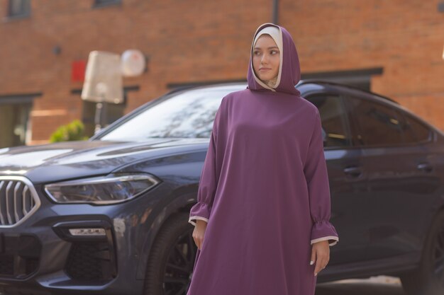 Islamic beautiful woman in a Muslim dress standing on a summer park street background forest autumn trees.world hijab day.