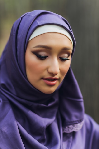 Islamic beautiful woman in a Muslim dress standing on a summer park street background forest autumn trees.world hijab day.