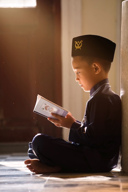 An Islamic child prays to study with his sister and brother in a mosque in Songkhla, Thailand.