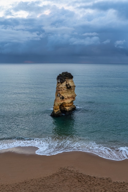 Islet rock on Dona Ana beach with dramatic sky in Lagos Algarve Portugal