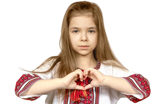 Isolate a girl in national Ukrainian clothes vyshyvanka shows a heart sign as a sign of love for Ukraine closeup The concept of peace in Ukraine