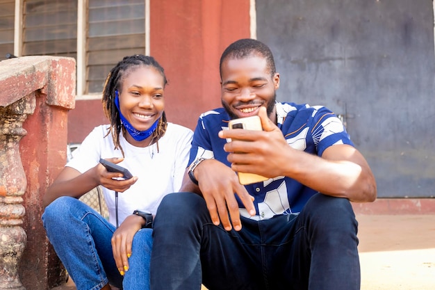 Isolated african guy and mixed race girl holding electronic devices mobile phones Share photos talk about new applications have fun with gadgets and learn about modern wireless technology