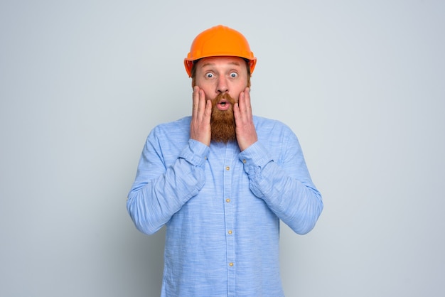 Isolated amazed architect with beard and orange helmet